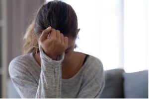 A woman sitting in the living room is depressed and upset due to untreated IBS